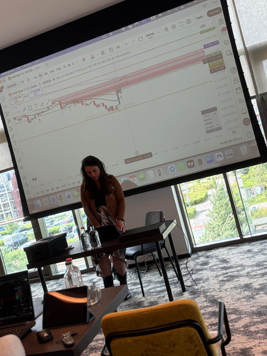 Presenter at the laptop as a candlestick chart fills the screen behind her.